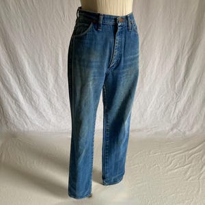 Pu&ograve; includere: Jeans blu in denim a vita alta e gamba dritta. I jeans hanno un classico design a cinque tasche e una chiusura con bottone e cerniera. Il denim ha un lavaggio sbiadito.