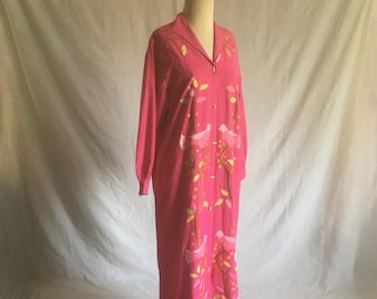 May include: A long pink dress with a white collar and long sleeves. The dress has a floral pattern with birds and leaves embroidered in white, pink, and gold thread.