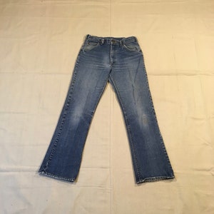 May include: A pair of blue denim jeans with a straight leg fit. The jeans have a button fly and five pockets.