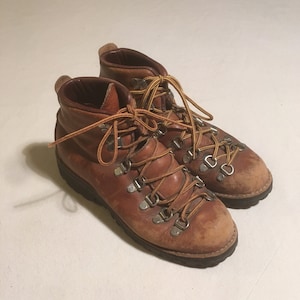 May include: A pair of brown leather hiking boots with laces and metal eyelets.