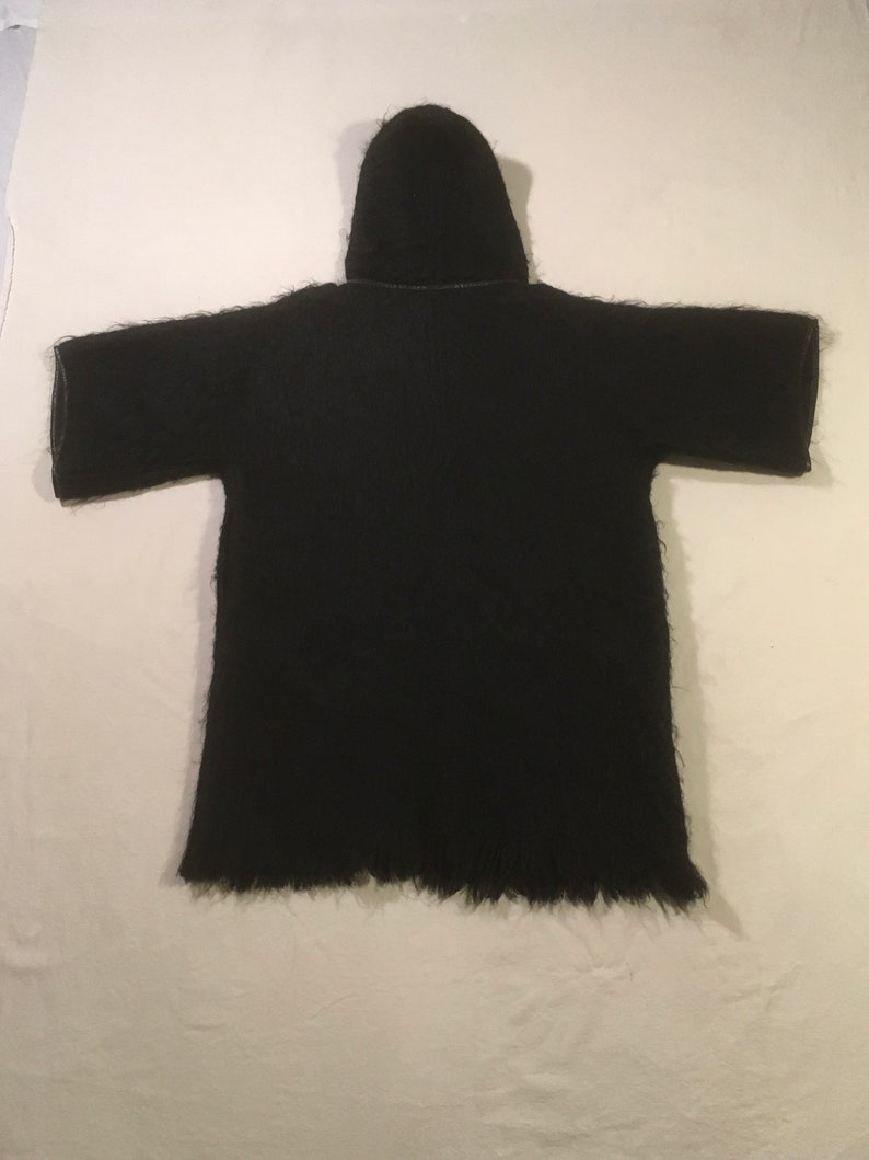 May include: Black hooded cardigan with a long, fringed hem. The cardigan is made of a soft, fuzzy material.