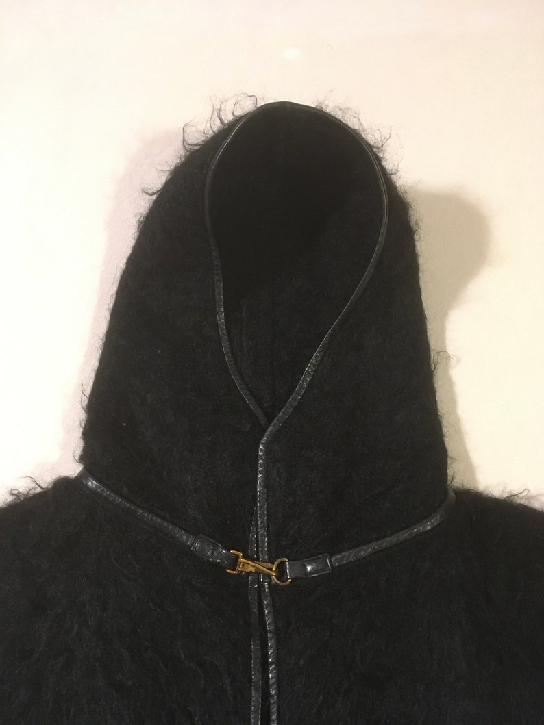 May include: Black hooded cape with a leather trim and a gold clasp.