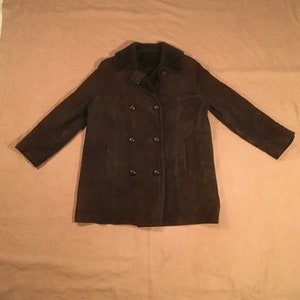 Puede incluir: Un abrigo marrón de ante de doble botonadura con cuello de piel.