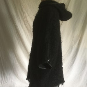 May include: Black hooded sweater with a fuzzy texture and leather trim on the sleeves and hood.