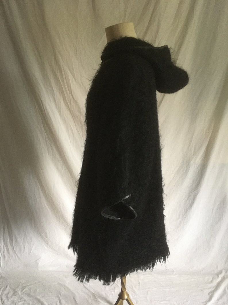 May include: Black hooded sweater with a fuzzy texture and leather trim on the sleeves and hood.
