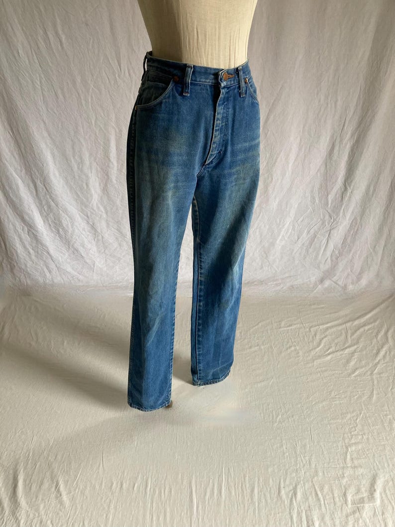 Pu&ograve; includere: Jeans blu in denim a vita alta e gamba dritta. I jeans hanno un classico design a cinque tasche e una chiusura con bottone e cerniera. Il denim ha un lavaggio sbiadito.