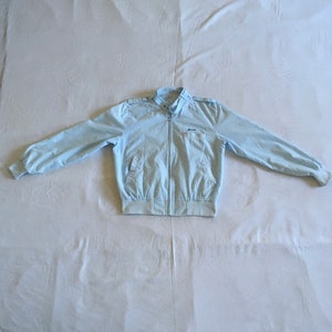 May include: A light blue jacket with a zipper closure and a small logo on the left chest.