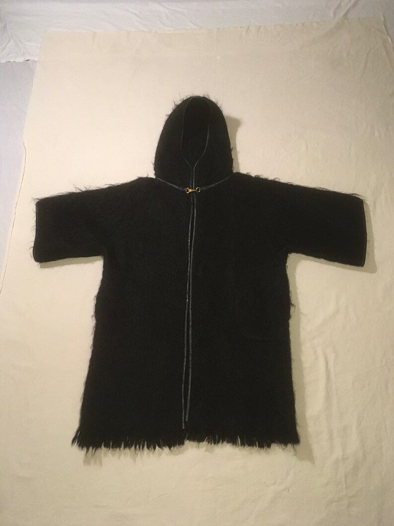 May include: A black hooded robe with a zipper closure and a fringed hem.