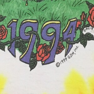 May include: A white t-shirt with a tie-dye pattern in shades of yellow, orange, and red. The shirt features a purple 1994 with yellow outlines and red roses. The text "&copy; 1994 GDM, Inc." is printed in black at the bottom.