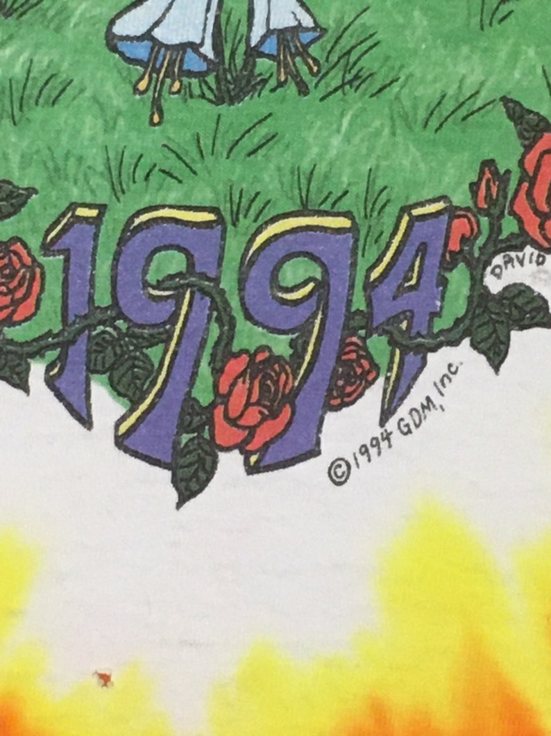 May include: A white t-shirt with a tie-dye pattern in shades of yellow, orange, and red. The shirt features a purple 1994 with yellow outlines and red roses. The text "&copy; 1994 GDM, Inc." is printed in black at the bottom.