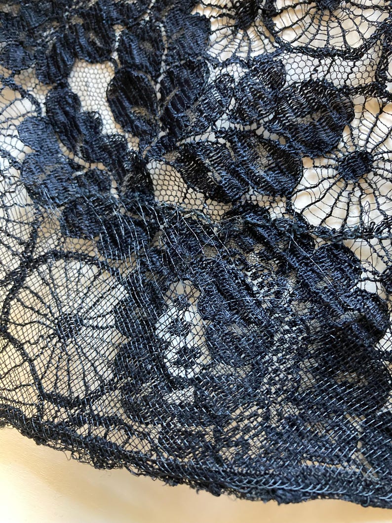 May include: Black lace fabric with a floral pattern. The lace is delicate and intricate, with a fine mesh background.
