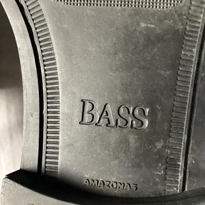 May include: Close-up of a black shoe sole with the embossed word "BASS" and the word "AMAZONAS" underneath. The sole has a textured pattern and a ridged border.