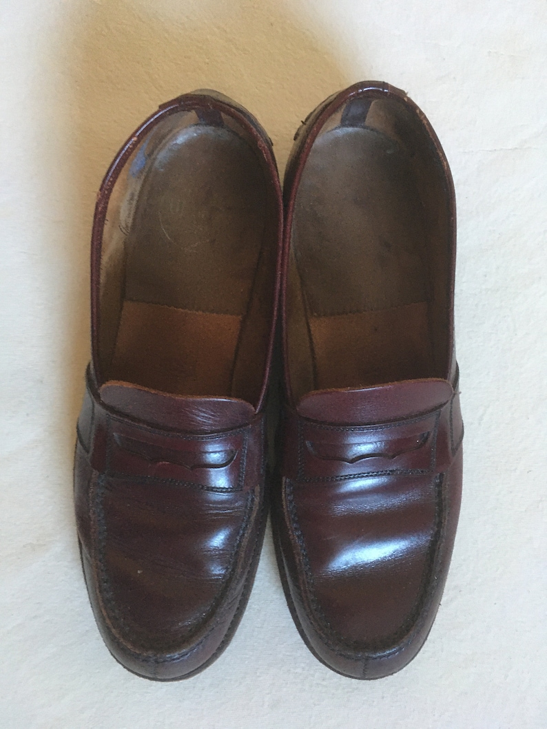 May include: A pair of dark brown leather loafers with a simple design. The loafers have a rounded toe and a single strap across the vamp.