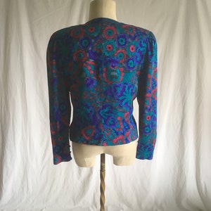 Op de afbeelding: Een blauwe en roze bloemenprint blouse met lange mouwen. De blouse heeft een V-hals en een aansluitende pasvorm.