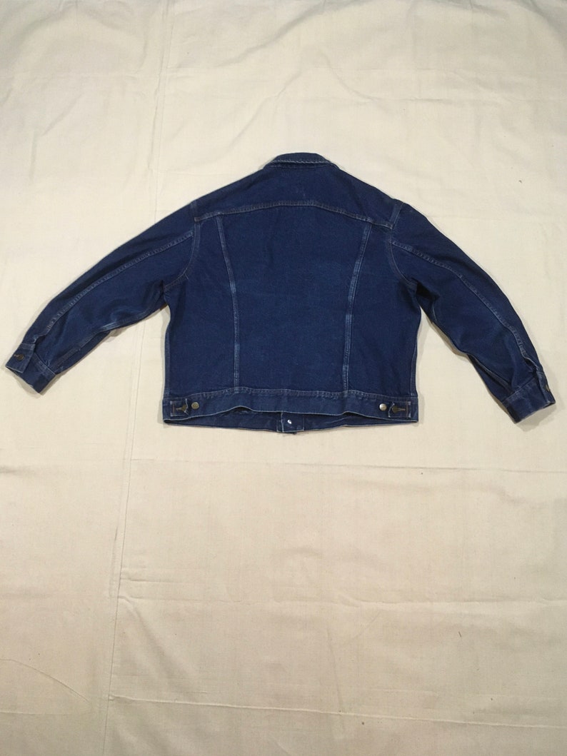 Op de afbeelding: Een donkerblauw denim jack met een knoopsluiting en lange mouwen.