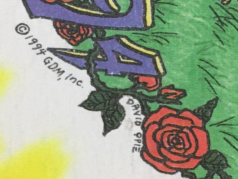 May include: A white t-shirt with a purple, yellow, and green design featuring a rose and the text "&copy; 1994 GDM, Inc. DAVID SPIE"