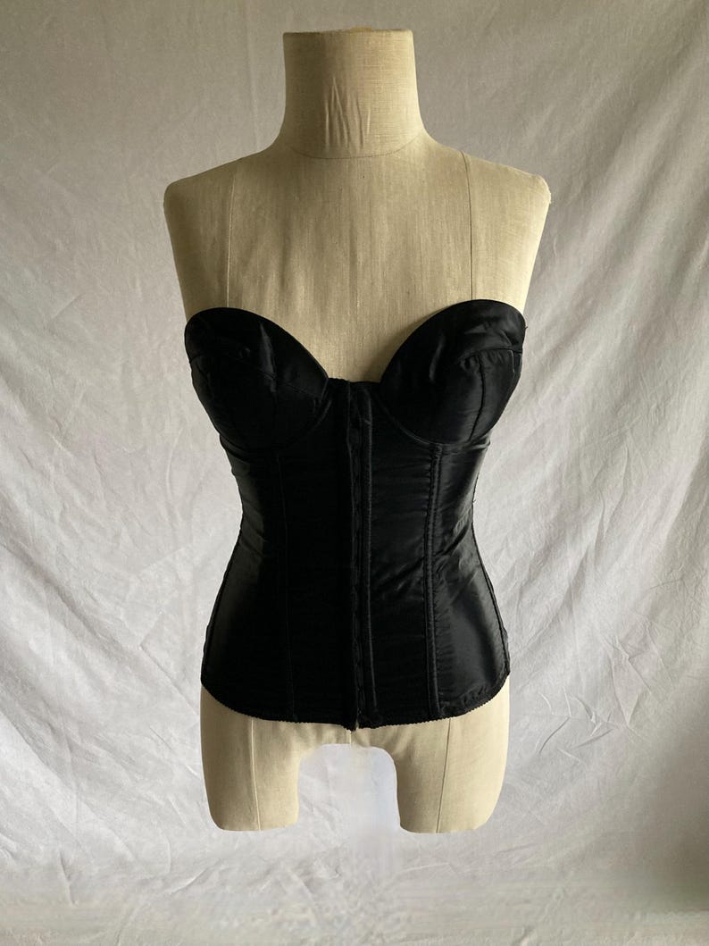 May include: A black satin strapless corset with boning and a lace-up front.