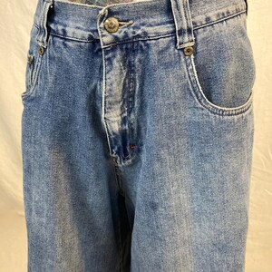 K&ouml;nnte beinhalten: Hellblaue Jeans mit Knopfverschluss und Vordertaschen. Die Jeans haben eine verwaschene Waschung und ein klassisches F&uuml;nf-Taschen-Design. Die Jeans sind im Vintage-Stil.