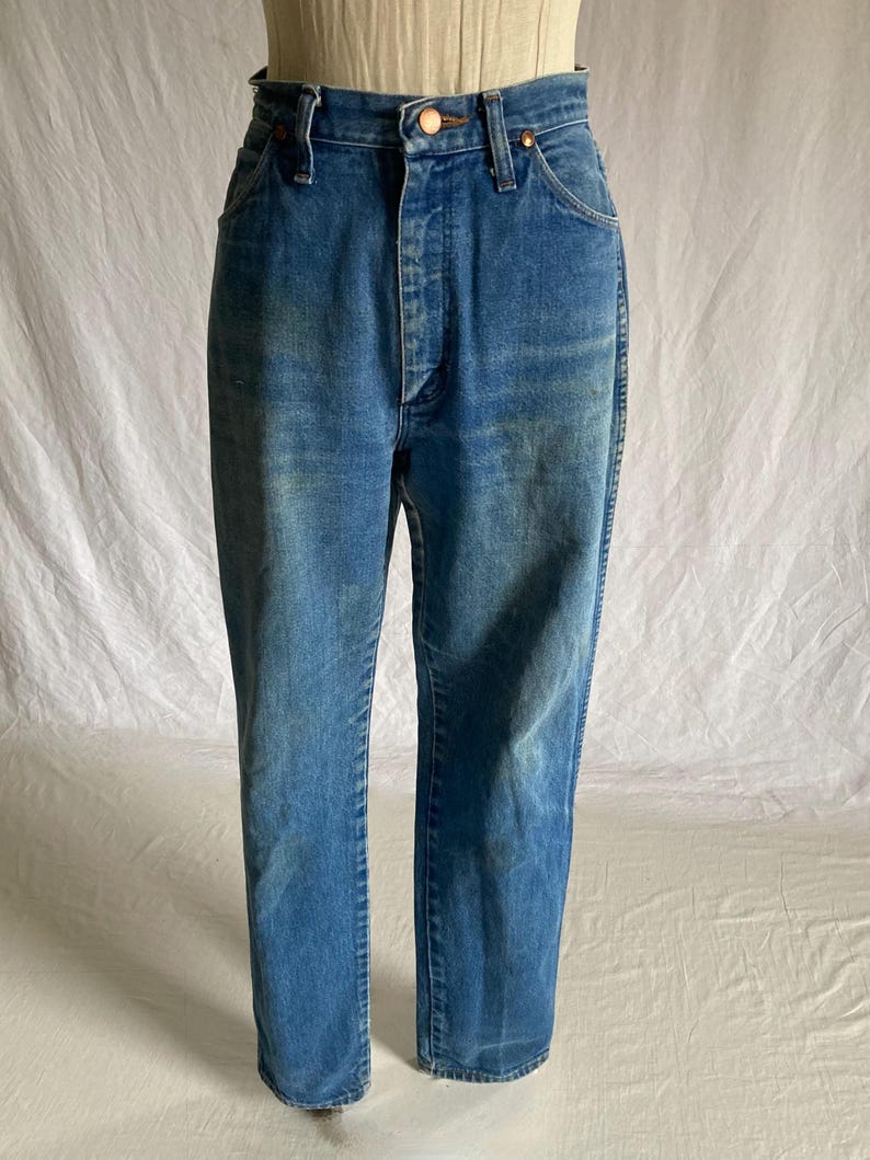 Pu&ograve; includere: Jeans blu in denim con chiusura a bottone e cerniera. I jeans hanno un classico design a cinque tasche e una vestibilit&agrave; a gamba dritta. Il denim ha un lavaggio sbiadito, che conferisce ai jeans un aspetto vintage.