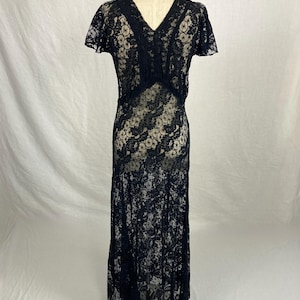 May include: A black lace maxi dress with a V-neckline and short sleeves. The dress is sheer and has a floral pattern.