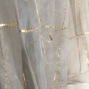 May include: White sheer fabric with a grid pattern of gold thread.