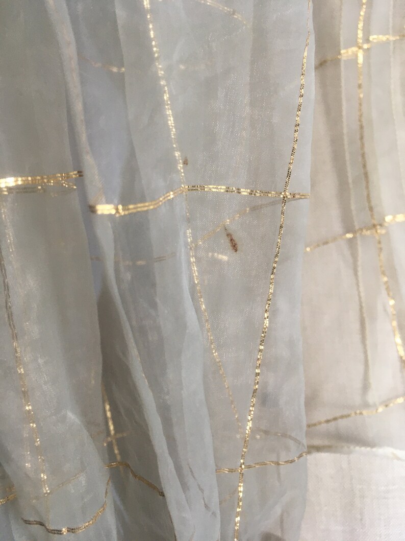 May include: White sheer fabric with a grid pattern of gold thread.