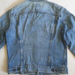 May include: A light blue denim jacket with a button closure and two pockets on the bottom.
