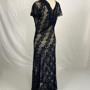 May include: A black lace dress with a V-neckline and short sleeves. The dress has a fitted bodice and a flowing skirt.