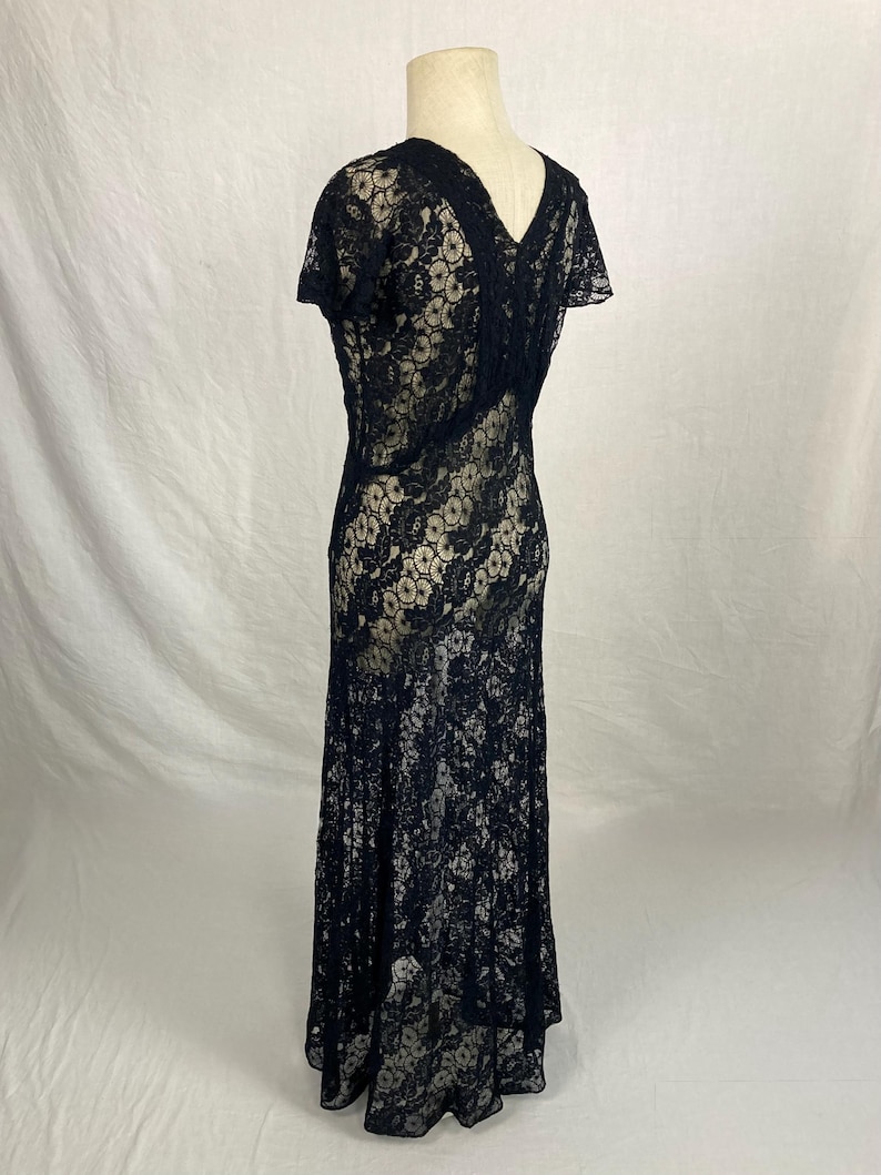 May include: A black lace dress with a V-neckline and short sleeves. The dress has a fitted bodice and a flowing skirt.