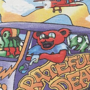 May include: A purple and orange psychedelic van with the words "Grateful Dead" on the side. A red airplane with a skull and crossbones flies above the van. The van has a green creature in the driver's seat and a red bear with sunglasses in the passenger seat.