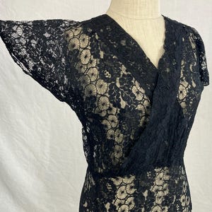 May include: A black lace dress with a V-neckline and short sleeves. The dress has a floral pattern and is made of a delicate fabric.