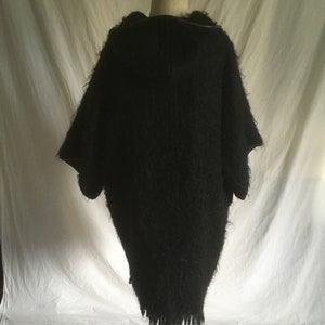 May include: Black fuzzy hooded sweater with a long, loose fit and a frayed hem.