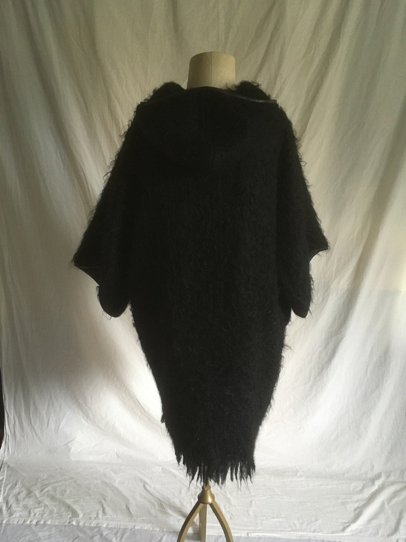 May include: Black fuzzy hooded sweater with a long, loose fit and a frayed hem.
