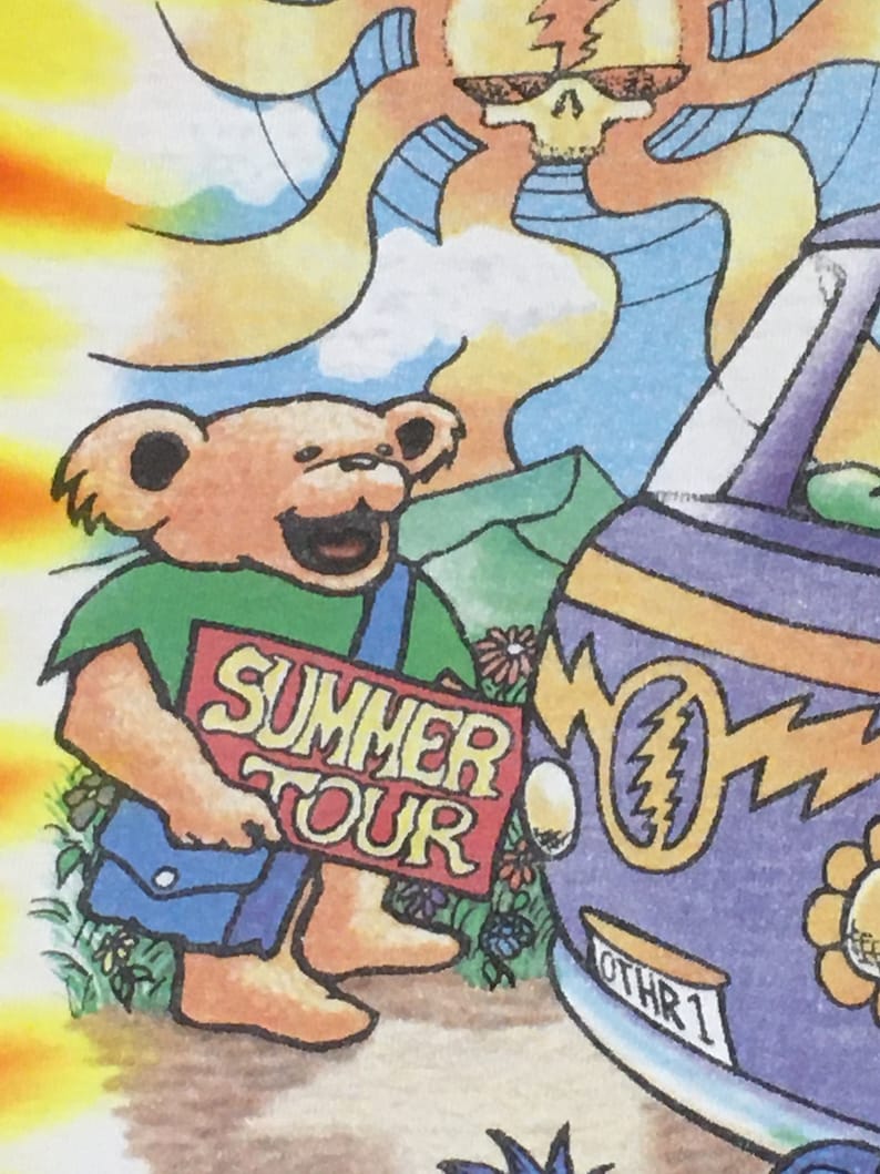May include: A cartoon illustration of a brown bear holding a red sign that says "Summer Tour". The bear is wearing a green shirt and blue overalls. The bear is standing next to a purple van with a lightning bolt symbol and the text "Othr 1" on the side.