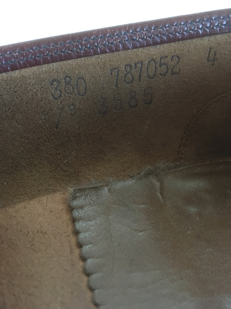 May include: Close-up of the inside of a brown leather shoe with the numbers 380 787052 4 3685 printed on the insole.