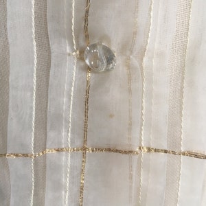 May include: White sheer fabric with gold stripes and a clear crystal button.