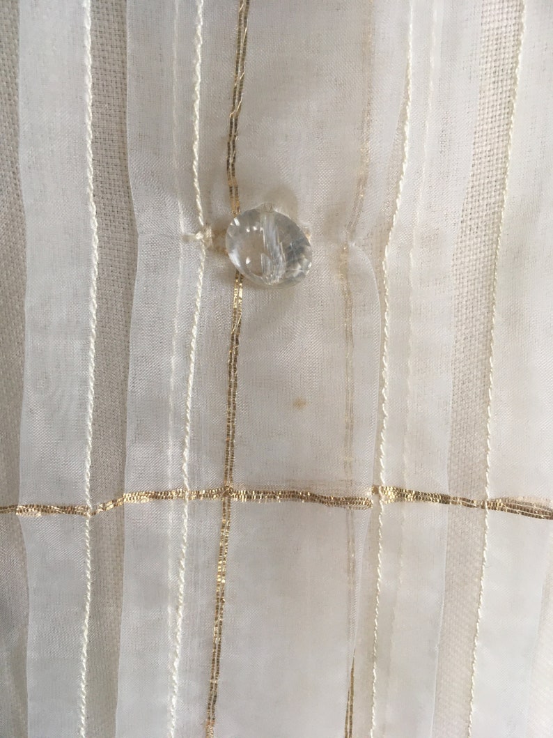 May include: White sheer fabric with gold stripes and a clear crystal button.