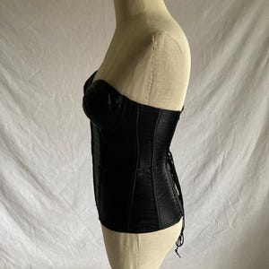 May include: A black satin corset with boning and a lace-up back.