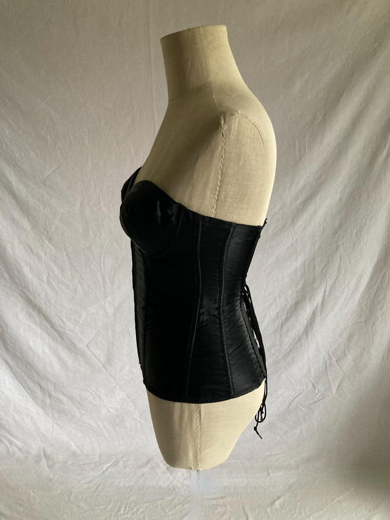 May include: A black satin corset with boning and a lace-up back.