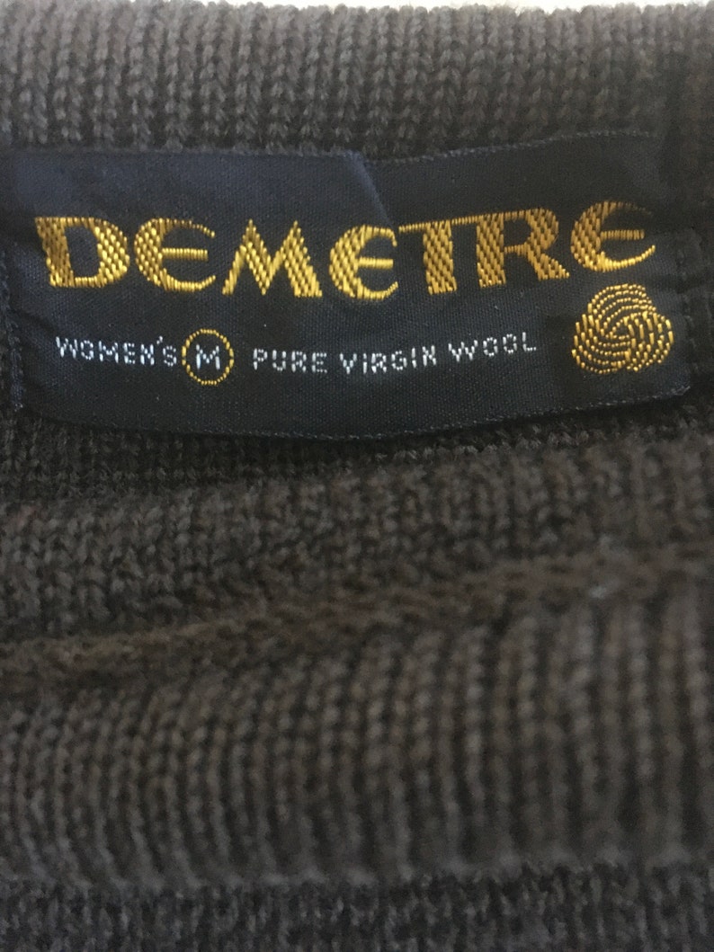 May include: A black label with gold lettering that reads "Demetre" and "Women's M Pure Virgin Wool".