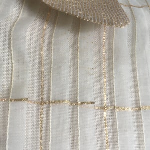 May include: White sheer fabric with gold stripes and a gold bow at the top.