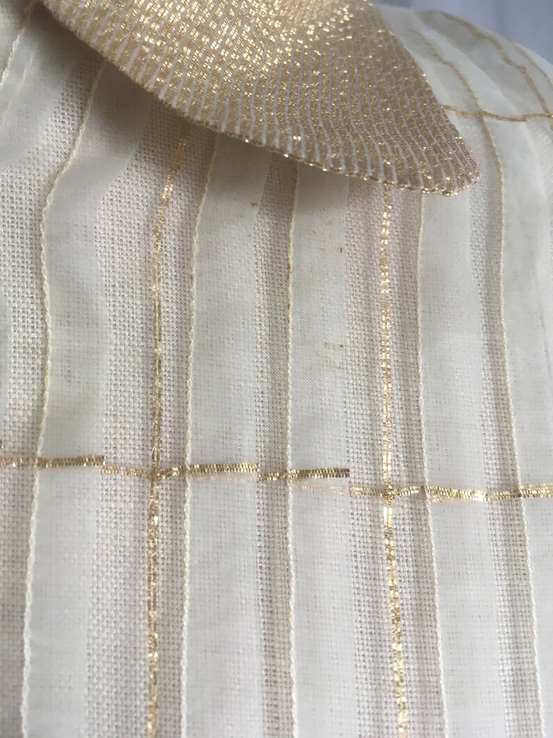 May include: White sheer fabric with gold stripes and a gold bow at the top.