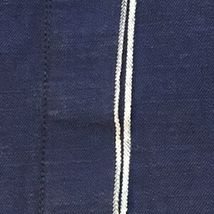 May include: Close-up of a dark blue fabric with two white stripes running vertically down the center.