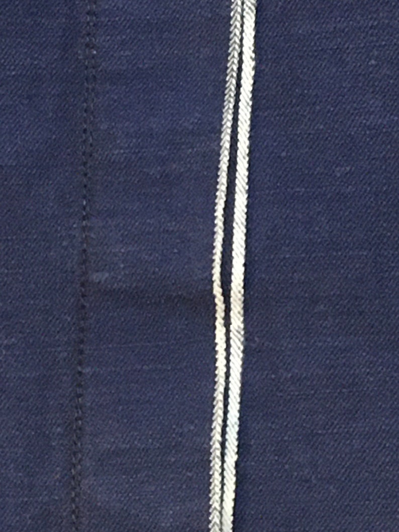 May include: Close-up of a dark blue fabric with two white stripes running vertically down the center.