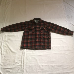 May include: A red and black checked flannel shirt with long sleeves and two chest pockets.