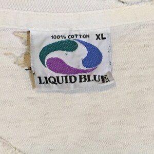 May include: White Liquid Blue brand t-shirt tag with a blue, green, and purple logo. The tag says "100% Cotton" and "XL".