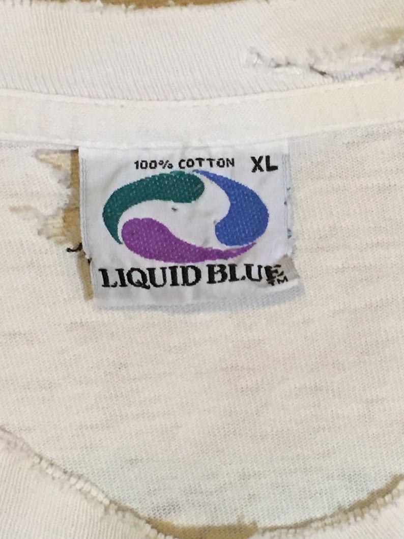 May include: White Liquid Blue brand t-shirt tag with a blue, green, and purple logo. The tag says "100% Cotton" and "XL".