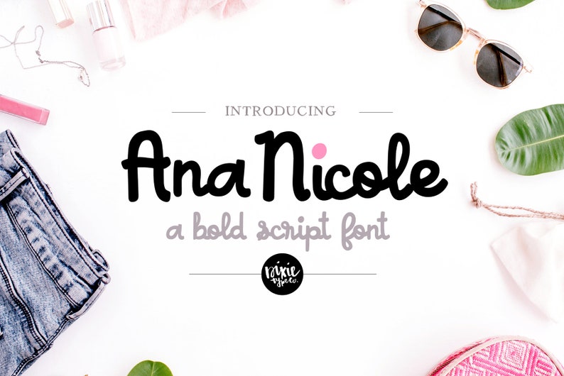 May include: Introducing Ana Nicole, a bold script font. The text is in black with a pink dot above the word "Nicole". The text is on a white background with various objects around it, including a pair of sunglasses, a piece of fabric, and a plant.