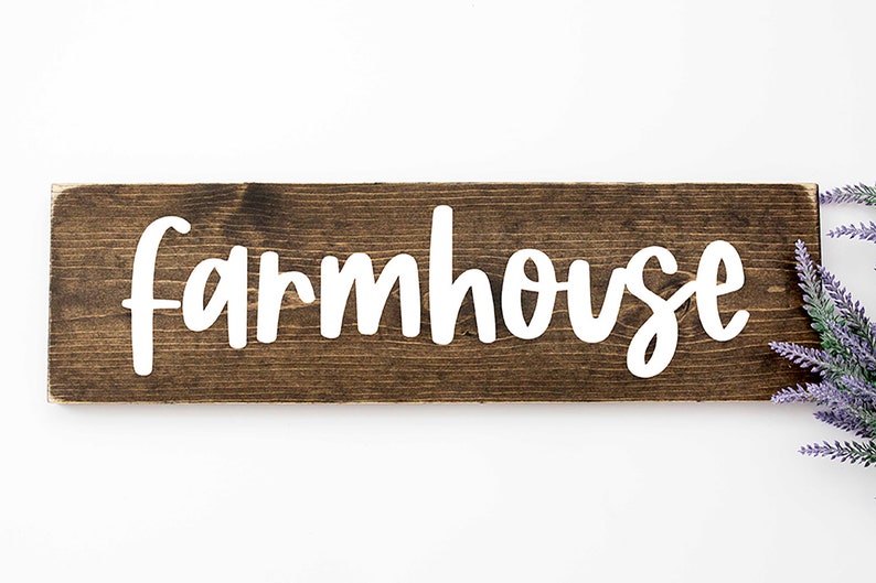 May include: A rustic wooden sign with the word "farmhouse" painted in white on a dark brown background.