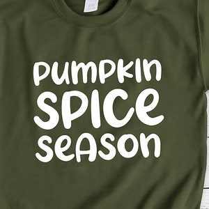May include: A green sweatshirt with the text "pumpkin spice season" in white lettering.